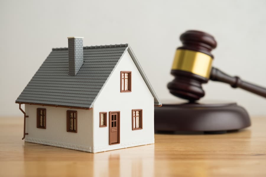 Model house beside a wooden gavel representing a property auction, symbolising a career in real estate auctioneering